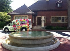 A Mancusos-branded van makes its delivery behind a babbling water fountain